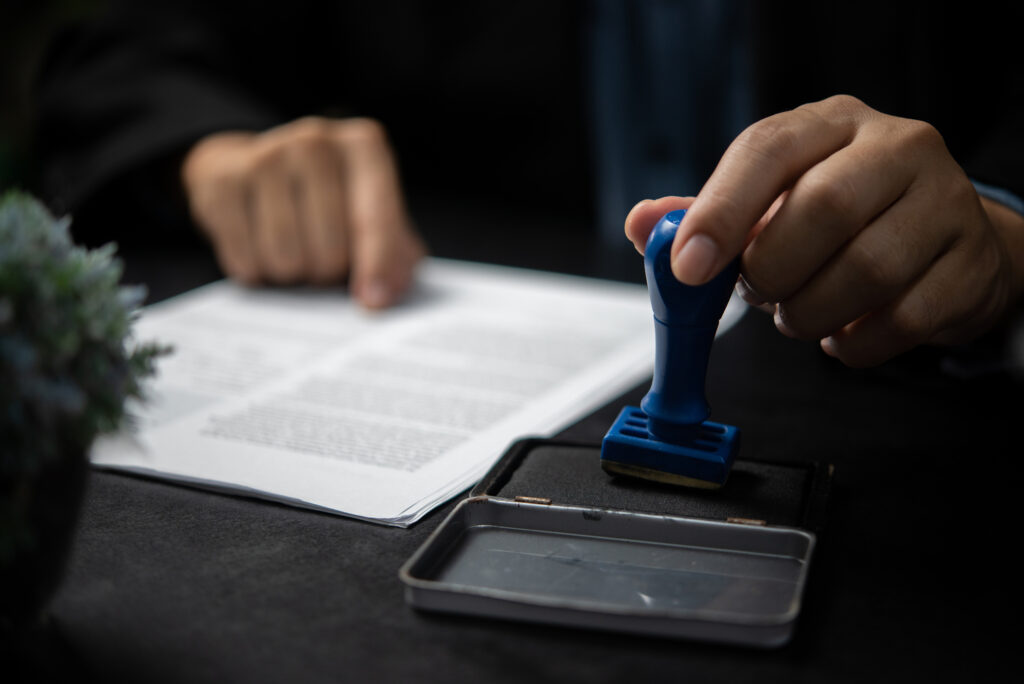 Man stamping approval of work finance banking or investment marketing documents on desk.